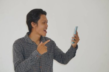 Siyah tişörtlü genç Asyalı adam akıllı telefona bakarken şaşırdı.