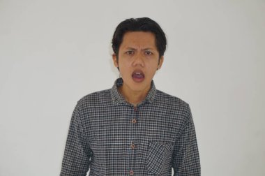 Beyaz arka planda siyah gömlekli Asyalı genç adamın şaşırmış ifadesi..