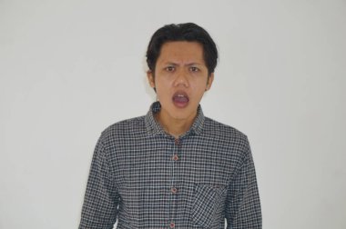 Beyaz arka planda siyah gömlekli Asyalı genç adamın şaşırmış ifadesi..