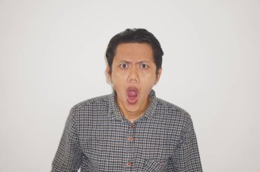 Beyaz arka planda siyah gömlekli Asyalı genç adamın şaşırmış ifadesi..