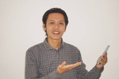 Cep telefonunu tutarken mutlu bir yüz ifadesi gösteren genç bir Asyalı..