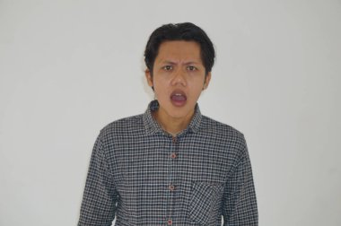 Beyaz arka planda siyah gömlekli Asyalı genç adamın şaşırmış ifadesi..