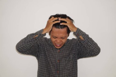 Genç Asyalı bir adam stres jesti göstererek başını tutuyor. beyaz arkaplanda izole edilmiş 