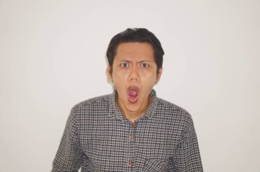 Beyaz arka planda siyah gömlekli Asyalı genç adamın şaşırmış ifadesi..