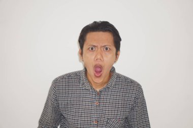 Beyaz arka planda siyah gömlekli Asyalı genç adamın şaşırmış ifadesi..