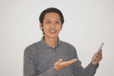 Cep telefonunu tutarken mutlu bir yüz ifadesi gösteren genç bir Asyalı..