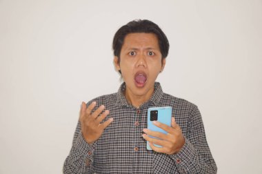 Siyah tişörtlü genç Asyalı adam beyaz arka planda izole edilmiş akıllı telefona bakarken şaşırdı..