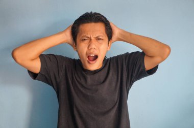 Beyaz arka planda siyah tişörtlü Asyalı genç adamın şaşırmış ifadesi..