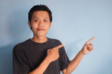 Siyah tişört giyen genç bir Asyalı hoş geldin jesti yapıyor ya da...