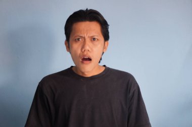 Siyah tişörtlü Asyalı genç adamın şaşırmış ifadesi.