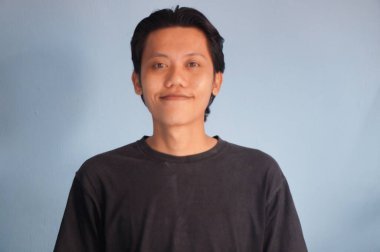 Siyah tişörtlü kameraya gülümseyen genç Asyalı adam.