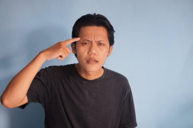 Genç Asyalı bir adam bir şeyler düşünüyor. izole edilmiş mavi arkaplan