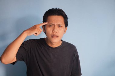 Genç Asyalı bir adam bir şeyler düşünüyor. izole edilmiş mavi arkaplan