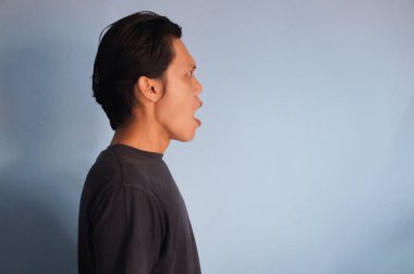 Siyah gömlekli Asyalı genç adamın şaşırmış ifadesi yana bak.