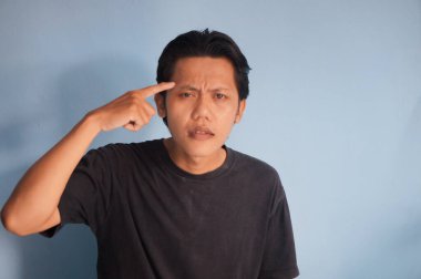 Genç Asyalı bir adam bir şeyler düşünüyor. izole edilmiş mavi arkaplan