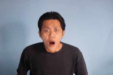 Siyah tişörtlü Asyalı genç adamın şaşırmış ifadesi.