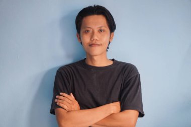 Siyah tişörtlü kameraya gülümseyen genç Asyalı adam.