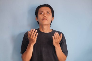 Asyalı genç bir adam dua ediyor, ahenk içinde ve Tanrı 'ya inanarak mutlu bir hayat sürüyor.