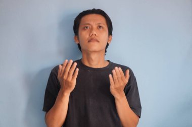 Asyalı genç bir adam dua ediyor, ahenk içinde ve Tanrı 'ya inanarak mutlu bir hayat sürüyor.