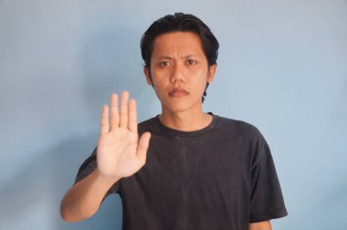 Siyah tişörtlü genç Asyalı yakışıklı adam dur hareketi yapıyor..