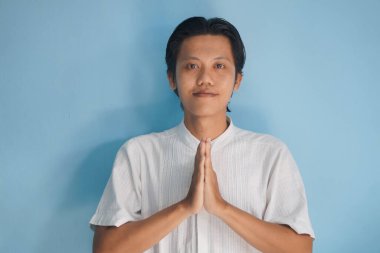 Beyaz elbiseli genç Asyalı Müslüman adam Ramazan 'da ve bayram kutlamalarında gülümsüyor..