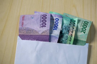 Beyaz bir zarfa Rupiah parası. Kurban Bayramı ya da bayram günlerinde THR