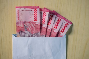 Beyaz bir zarfa Endonezya Rupiah parası. Uang 100.000 Rupiah, IDR 100.000, Kurban Bayramı 'nda THR