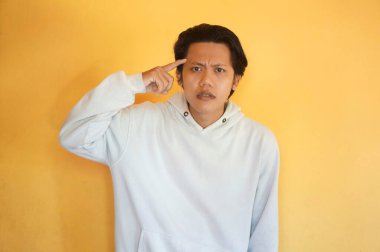 Asyalı genç bir adam bir şey düşünüyor. izole edilmiş sarı arkaplan.