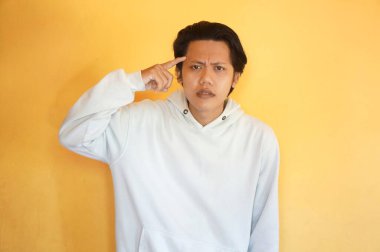 Asyalı genç bir adam bir şey düşünüyor. izole edilmiş sarı arkaplan.