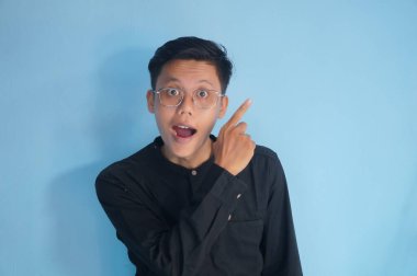 Siyah gömlekli yakışıklı Asyalı adam parmağını boş bir yere doğrultuyor. gösterme seçeneği, öneri, sunum