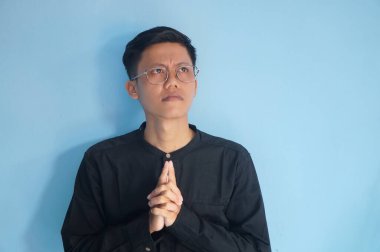 Asyalı genç adam bir şey düşünüyor. Gözleriyle bir jest yapıyor.