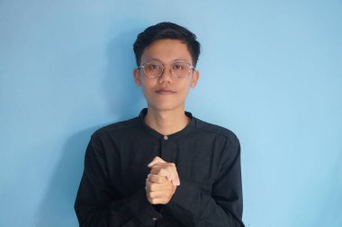 Ellerini çapraz yapıp kameraya bakan Asyalı genç bir adam.