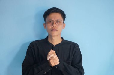 Ellerini çapraz yapıp kameraya bakan Asyalı genç bir adam.