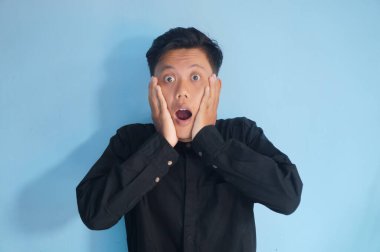 Siyah gömlekli genç Asyalı adamın şaşırmış ifadesi.