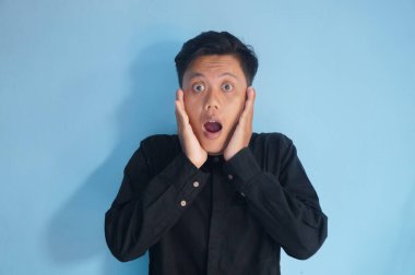 Siyah gömlekli genç Asyalı adamın şaşırmış ifadesi.