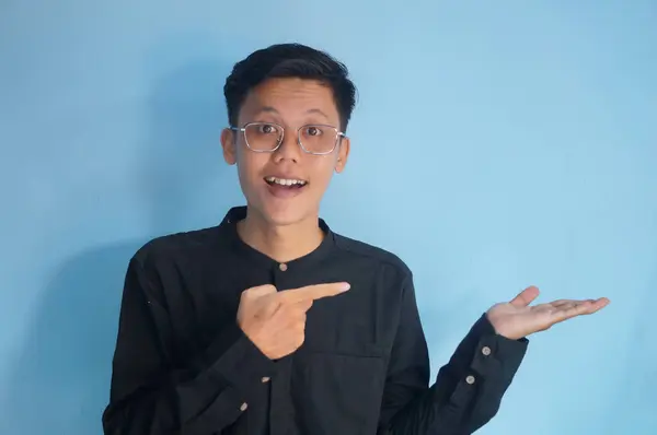 stock image Young asian man wearing black shirt smiling pointing with hand finger to the side