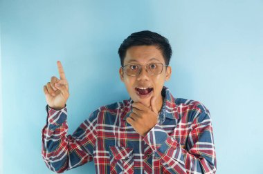 Kırmızı tişörtlü yakışıklı Asyalı parmağını boş bir yere doğrultuyor. gösterme seçeneği, öneri, sunum