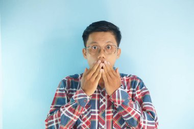 Şok olmuş genç Asyalı adam, eli ağzında.