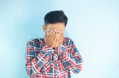 Ağlarken yüzünü ellerle kapatan üzgün yüzlü Asyalı genç adam. depresyon kavramı