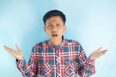 Kareli gömlek giyen Asyalı genç bir adamın yüzünde karışık bir ifade var.