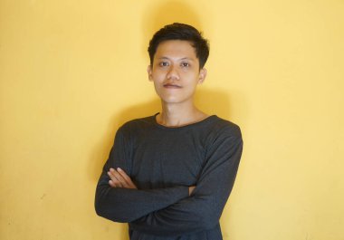 Kameraya bakarken siyah tişört giyen gülümseyen Asyalı genç adam.