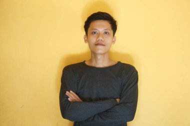 Kameraya bakarken siyah tişört giyen gülümseyen Asyalı genç adam.