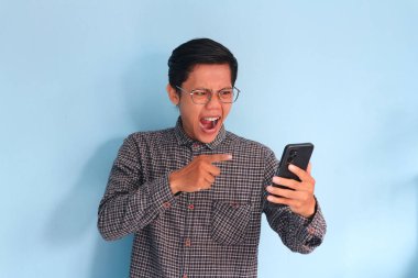 Sinirli genç Asyalı adam cep telefonunu işaret ediyor.