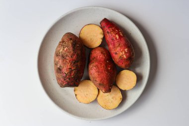 Beyaz arka planda, beyaz tabakta tatlı patates.