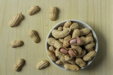 Ahşap bir arka planda kabuktaki soyulmamış fıstıklar.