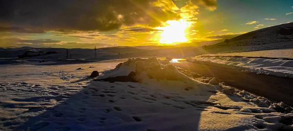 A dramatic sunset full of colors on a winter day with clouds and snow