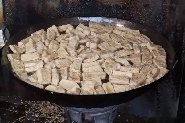 Büyük bir tavada pişirilene kadar haşlanmış tofuyu kazıma sürecine yakından bakın, ve bol yağlı.