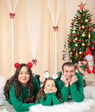 Mutlu bir aile Noel 'i evde kutluyor. Baba, anne ve yeşil kazaklı küçük kız. Yeni dairede bir aile.