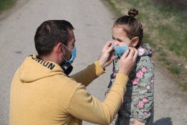 Maskeli ve koruyucu eldivenli baba ve kızı.