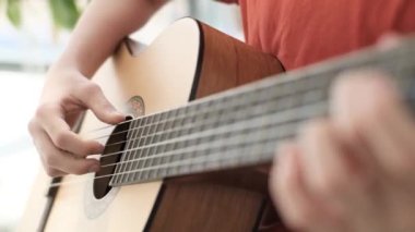 Evdeki kanepede otururken gitar çalan bir çocuğun yakın çekimi. Müzik aleti çalmayı öğrenme konsepti. Yüksek kalite 4k video. 